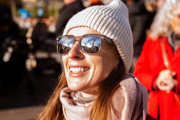 Smiling young woman in a hat with glasses on the street
