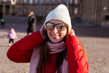 Smiling young woman in a hat with glasses on the street