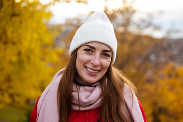Smiling young woman in a hat against the background of autumn trees