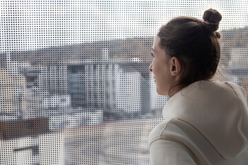 Young woman standing with her back looking out the panoramic window