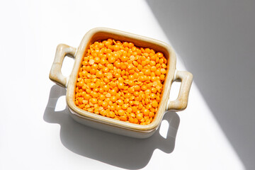 Bright orange lentils displayed in a ceramic dish under natural light