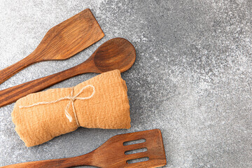 Wooden kitchen utensils and a cloth roll arranged on a gray countertop