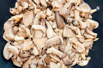 Freshly chopped Pleurotus mushrooms ready for cooking in a kitchen setting with natural lighting
