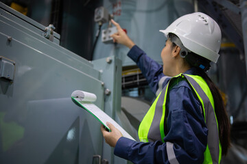Gas insulated switchgear substation engineer inspects equipment carefully while holding clipboard...