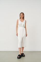 Beautiful female model poses in stylish white dress in indoor studio setting