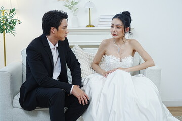 The groom in a black suit sits and talks with the bride in a white dress at a wedding.