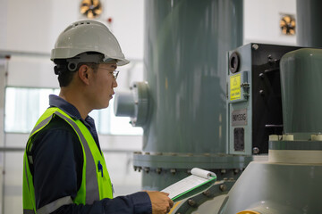 Gas insulated switchgear substation engineer inspects equipment carefully with clipboard in...