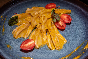 Boneless Duck Feet cold dish, a traditional Chinese cuisine dating back to imperial times. It is served with sliced tomatoes, and a light mustard sauce on a plate.