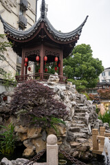 Fototapeta premium A traditional pavilion, adorned with red lanterns, is built atop rugged rocks at Qibao Ancient Town in Shanghai, China, reflecting classical Chinese architecture and garden design. 