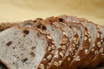 Close-up of freshly sliced oat bread with visible texture and oats on the crust, placed on burlap fabric.