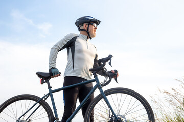 Bearded man cyclist stands with a bike against the blue sky. cycling and health hobbies