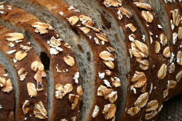 Close-up of freshly sliced oat bread with visible texture and oats on the crust, placed on burlap...