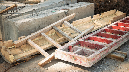 Construction site materials including wooden forms and concrete blocks at a busy building location during daylight hours