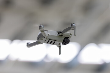 A compact, 249g grey drone hovers from a low angle, its propellers subtly blurred, suggesting it's...