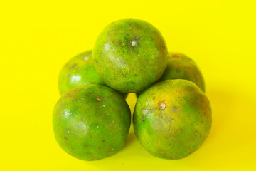 Fresh Green Orange on Bright Yellow Background is perfect for food marketing, tropical themes, health content, or naturally produced visuals.