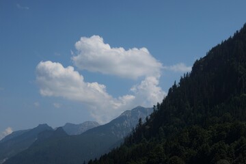 Clouds drift peacefully above the scenic mountains of the Füssen region in Germany during a sunny...
