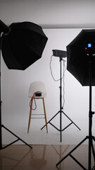Empty stool surrounded by professional lighting equipment in photo studio. 
