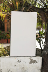 Empty outdoor information board placeholder. Small vertical billboard by the road in a small green city. billboard mock-up near the road; vertical blank advertising banner template on the street