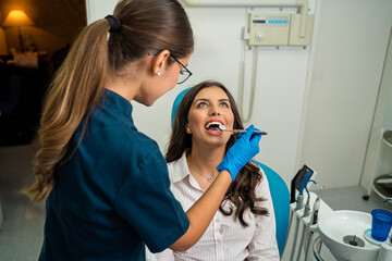 Beautiful , elegant young woman with beautiful white teeth having sitting in dentist chair and...