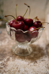 Ripe red cherries overflowing a glass bowl on rustic table
