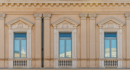 Obraz premium old yellow facade of house with three brown vintage wooden windows in retro italian european style