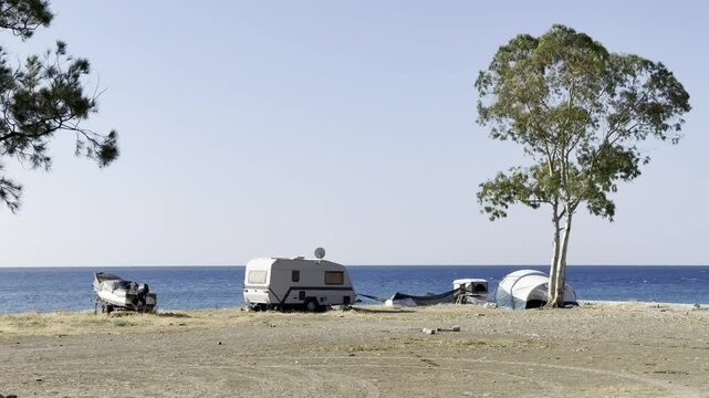 Camping on the seashore, tent, motorhome, boat and tree (horizontal)