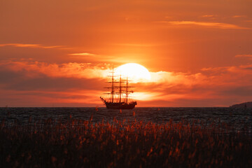 Silhouette of a historic sailing ship against the setting sun in Rocca al Mare, Tallinn. The sun is...