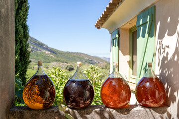 Four beautiful glass bottles filled with various fermented liquids arranged elegantly and displayed...
