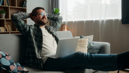 Happy smiling positive Caucasian man male guy at home couch sofa with laptop computer working...