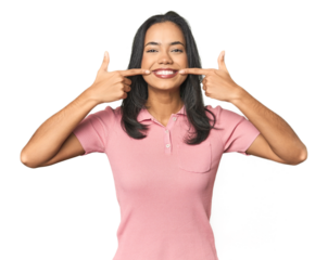 Simple portrait of a young Latina smiles, pointing fingers at mouth.