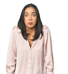 Simple portrait of a young Latina shrugs shoulders and open eyes confused.
