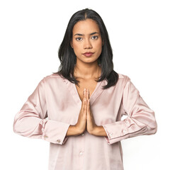 Simple portrait of a young Latina praying, showing devotion, religious person looking for divine...