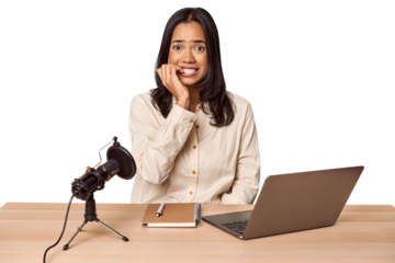 Woman records podcast with laptop biting fingernails, nervous and very anxious.