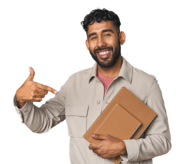 Hispanic student holding notebooks in studio person pointing by hand to a shirt copy space, proud and confident