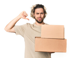 Young man with cardboard boxes in studio feels proud and self confident, example to follow.