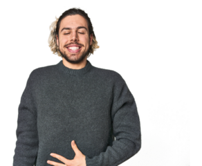 Young Caucasian man in studio setting touches tummy, smiles gently, eating and satisfaction concept.