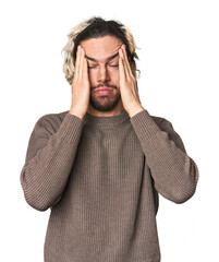 Young Caucasian man in studio setting touching temples and having headache.