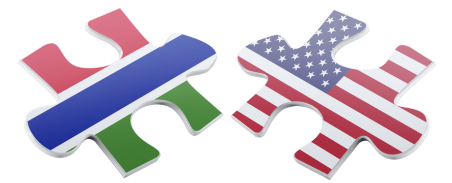 Two puzzle pieces, one depicting the flag of the Gambia and the other showing the American flag, are positioned next to each other, representing international cooperation.