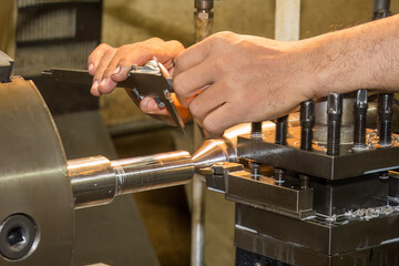 Close up scene the machine operator measuring dimension of turning parts by Vernier caliper.