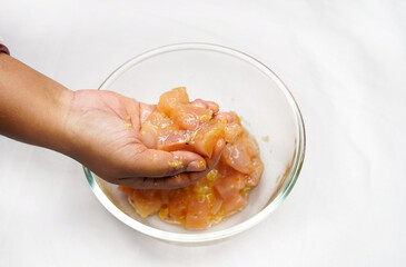 Indian woman's hands marinate chicken wings in soy sauce, eggs and garlic for chili chicken. Selective focus.