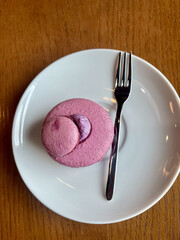 Purple berry macaron dessert with meringue on white plate. Elegant minimalistic presentation of French pastry. Close-up of gourmet sweet treat for bakery, cafe, or food blog concept.