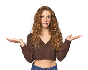 Fototapeta na wymiar Simple redhead studio portrait confused and doubtful shrugging shoulders to hold a copy space.