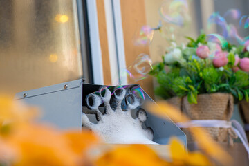 Close-up of a bubble machine in action at a wedding reception or children's party with floral decor