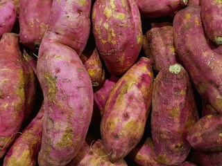 A close-up shot of a pile of fresh, vibrant purple sweet potatoes.