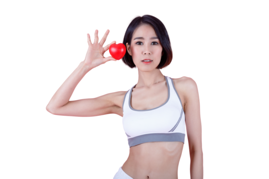 Fit Asian woman holding red heart-shaped stress ball symbolizing heart health. Promoting healthy lifestyle, fitness, wellness, and cardiovascular care on pink background.
