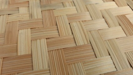 Close-up shot of intricately woven bamboo mat texture.  Natural light illuminates the warm, light...