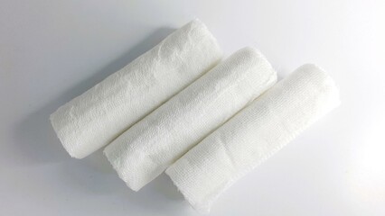 Three rolled gauze bandages on white background.  Perfect for medical, healthcare, first aid, or hygiene websites and designs.