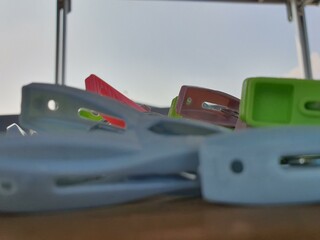Colorful clothespins closeup on wooden surface against a bright sky. Image shows various colors and...