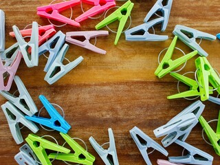 Colorful plastic clothespins arranged in a circle on a wooden background, leaving a central empty...