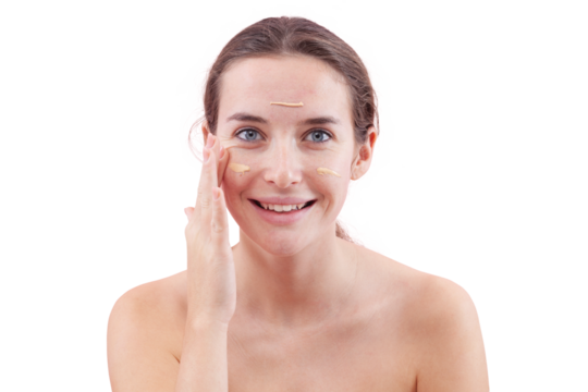 Smiling young woman with natural skin applying foundation cream on face. Visible makeup strokes. Beauty portrait, isolated on white background. Skincare and cosmetics routine, natural look concept. - Powered by Adobe